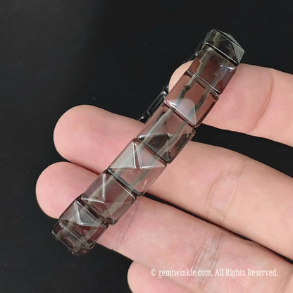 Angle view of translucent ice obsidian faceted pyramid square bead bracelet highlighting light dispersion across facets