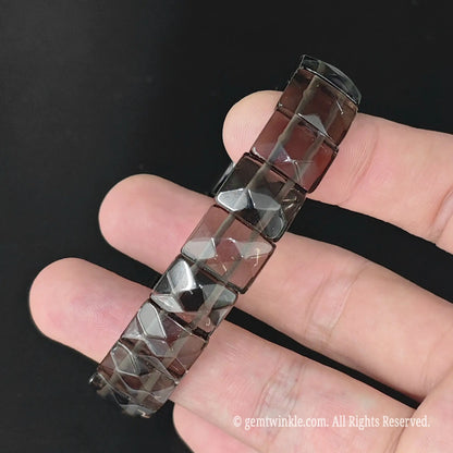 Angle view of translucent smoky obsidian faceted pyramid square bead bracelet highlighting light refraction through facets