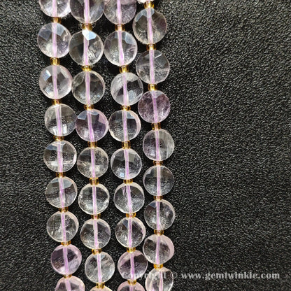 Vertical alignment of transparent pale amethyst faceted coin beads on dark background
