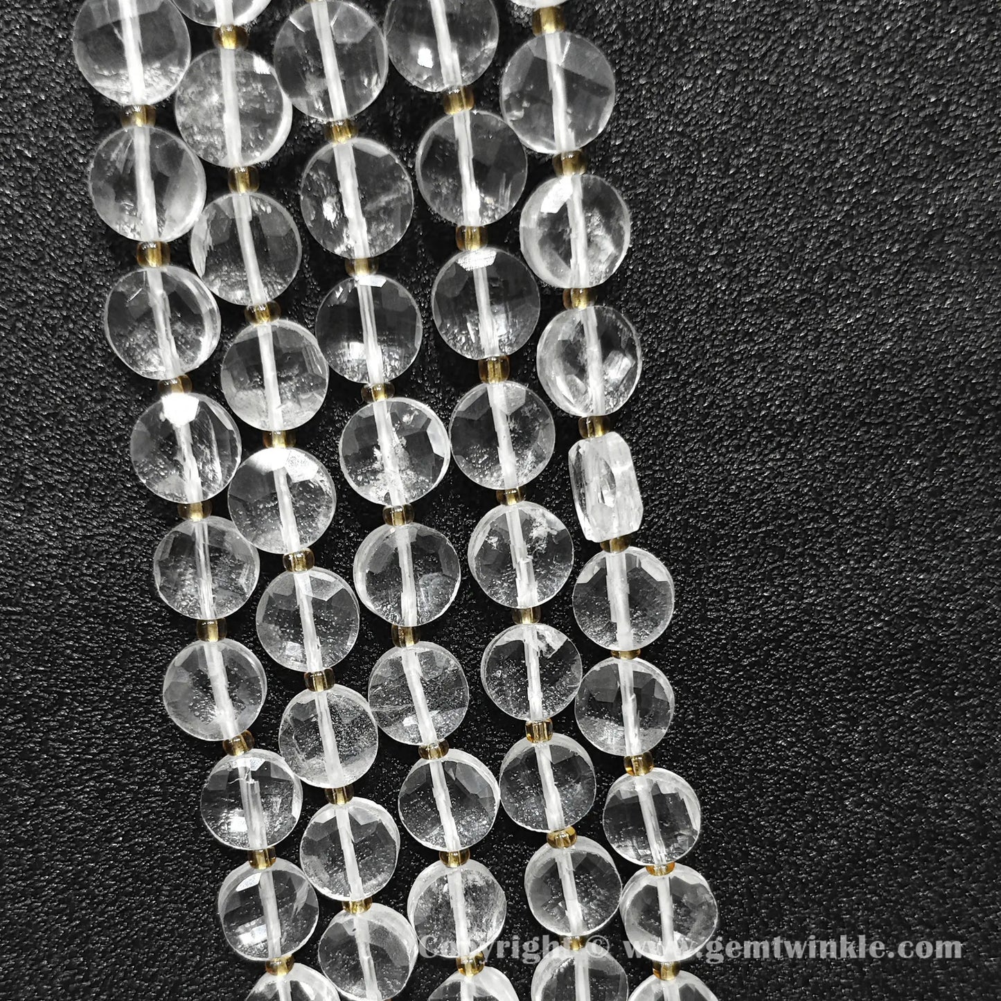 Vertical alignment of transparent clear quartz faceted flat disc beads on dark surface