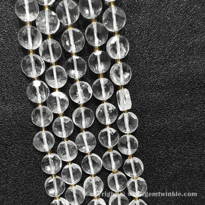 Vertical alignment of transparent clear quartz faceted flat disc beads on dark surface