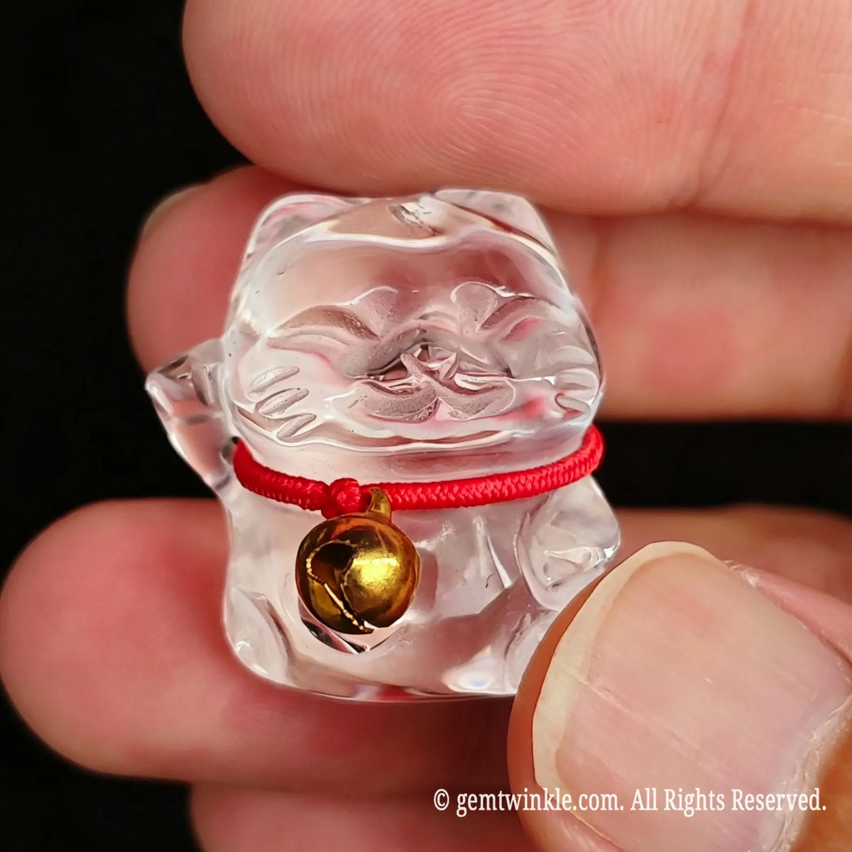 Back view of clear quartz fortune cat figurine showing smooth polished back and red cord knot