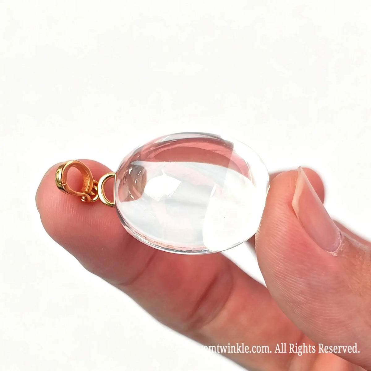 Side view of a clear quartz oval pendant showing high gloss surface and gold metal loop