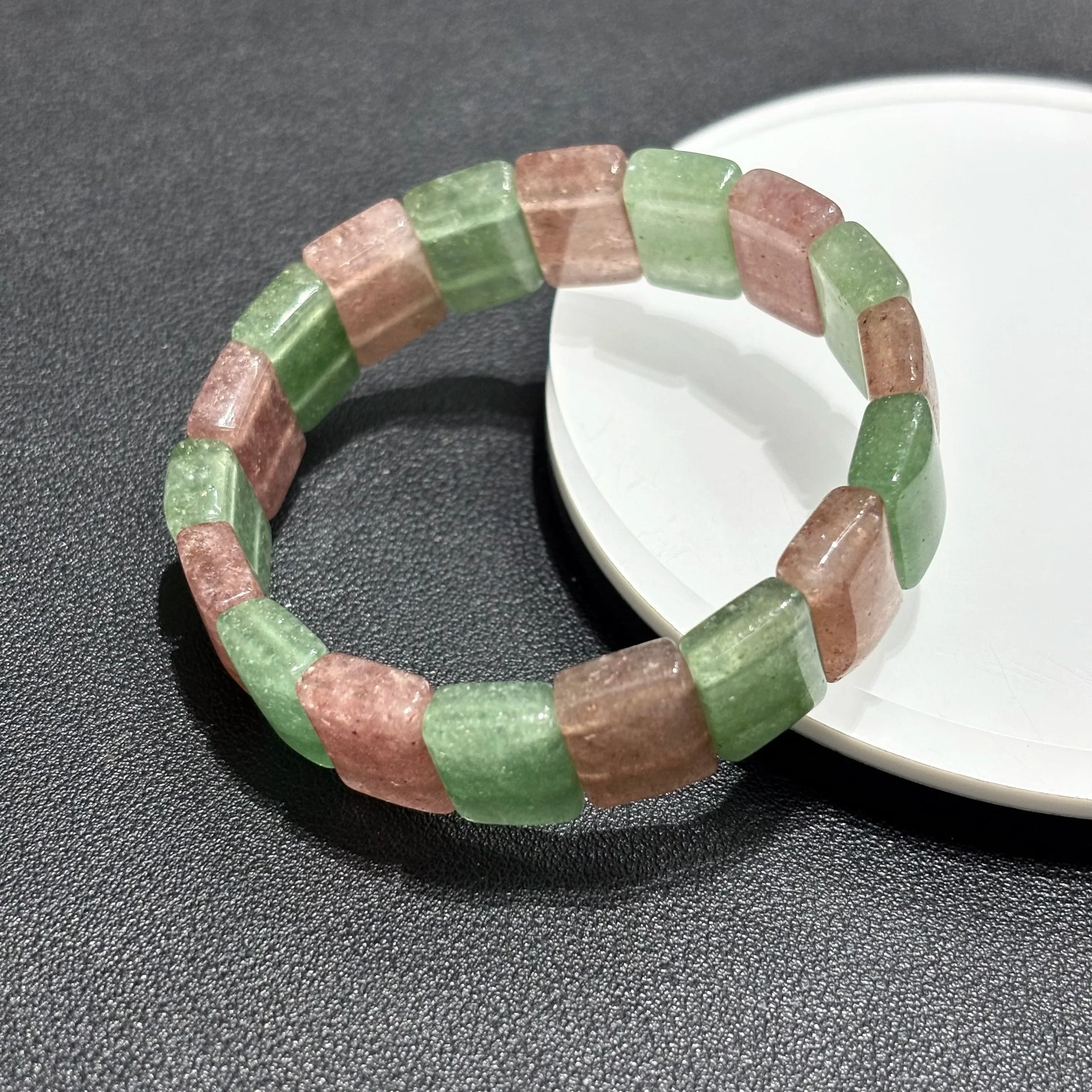 Two Natural Pink & Green Strawberry Quartz Bangle Bracelets arranged on a white plate, showcasing the elastic stretch and bead alignment.