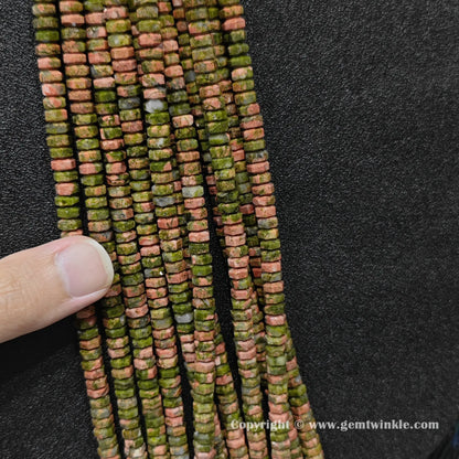 Close up view of 6x3mm unakite faceted disc rondelle beads inspected on fingers for quality preview