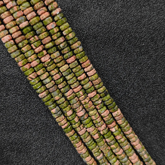 Macro closeup of natural unakite faceted rondelle beads 6x3mm showing light-reflecting green pink edges