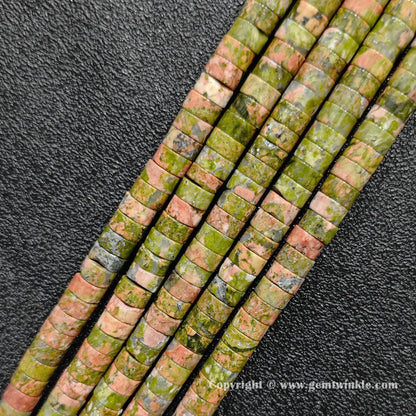 Angled view of natural unakite flat disc gemstone strands laid side by side on dark texture