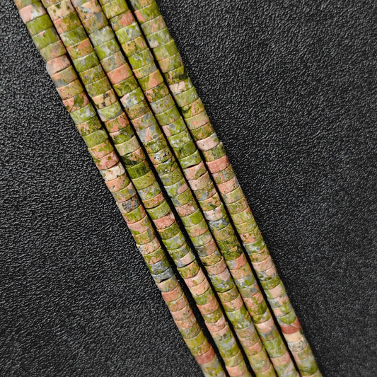 Macro closeup of natural unakite heishi rondelle beads 6x3mm showing green and pink mineral matrix