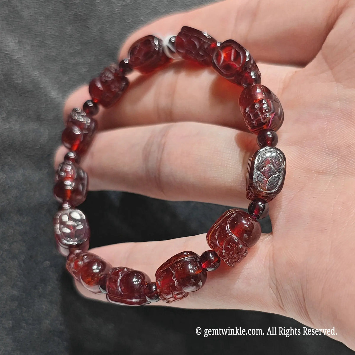 Perspective view of unisex garnet pixiu guardian bracelet resting on hand under studio lighting