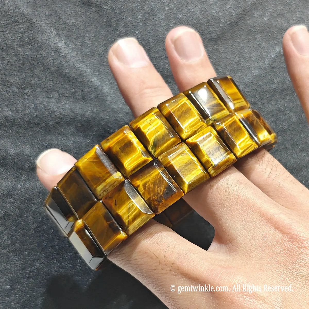 Full view of a unisex golden tiger eye gemstone cuff worn on hand under studio lighting