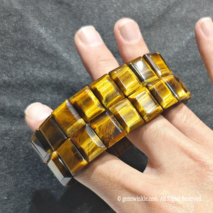 Full view of a unisex golden tiger eye gemstone cuff worn on hand under studio lighting
