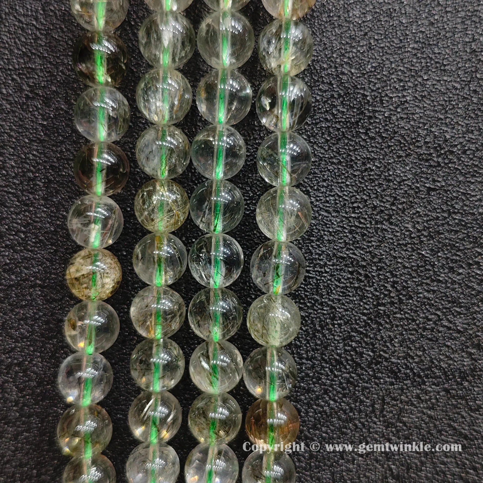 Close up view of untreated green hair crystal beading strands highlighting clear quartz transparency