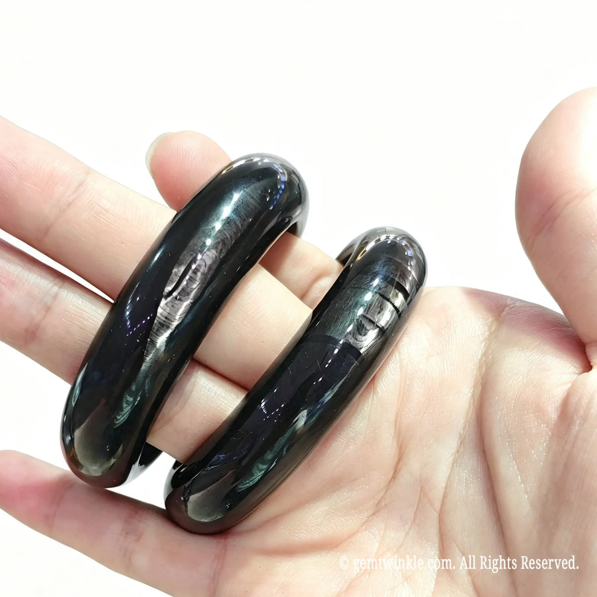 Hand holding velvet hypersthene stone bangles for live sale inventory and boutique reseller supply