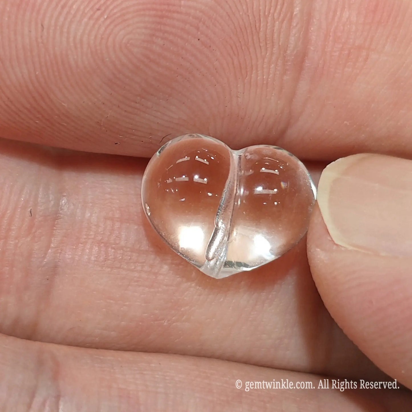 Vertical drilled clear quartz heart bead for diy jewelry making held in palm showing smooth glossy heart shape