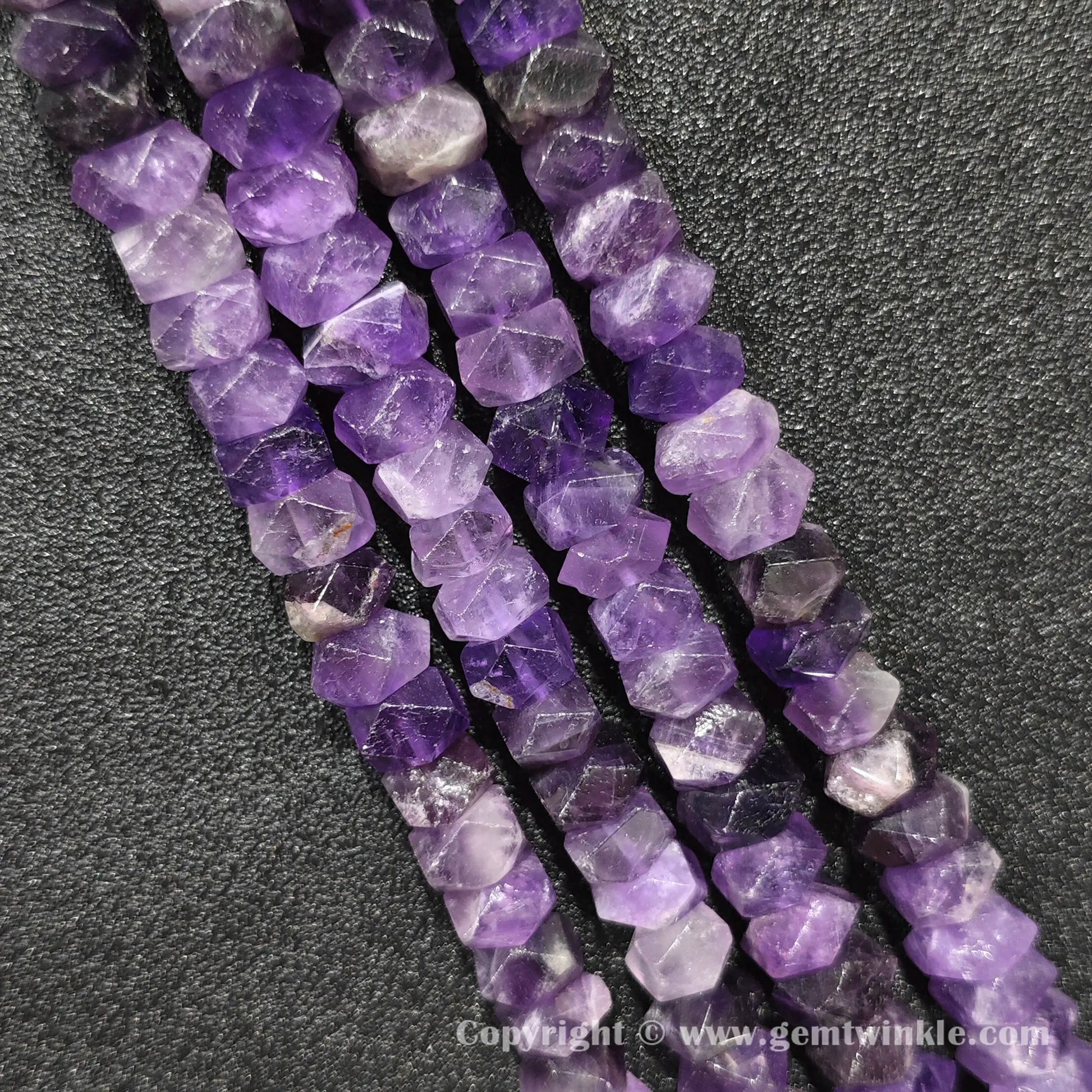 Vertical alignment of violet amethyst prismatic cylinder column beads on dark surface