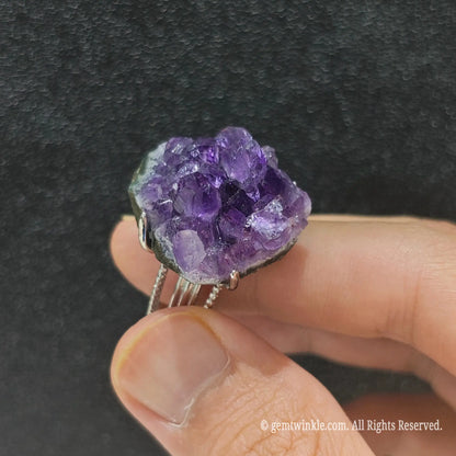 Violet amethyst crystal specimen ring side view held in hand showing organic raw cluster points and metal mounting
