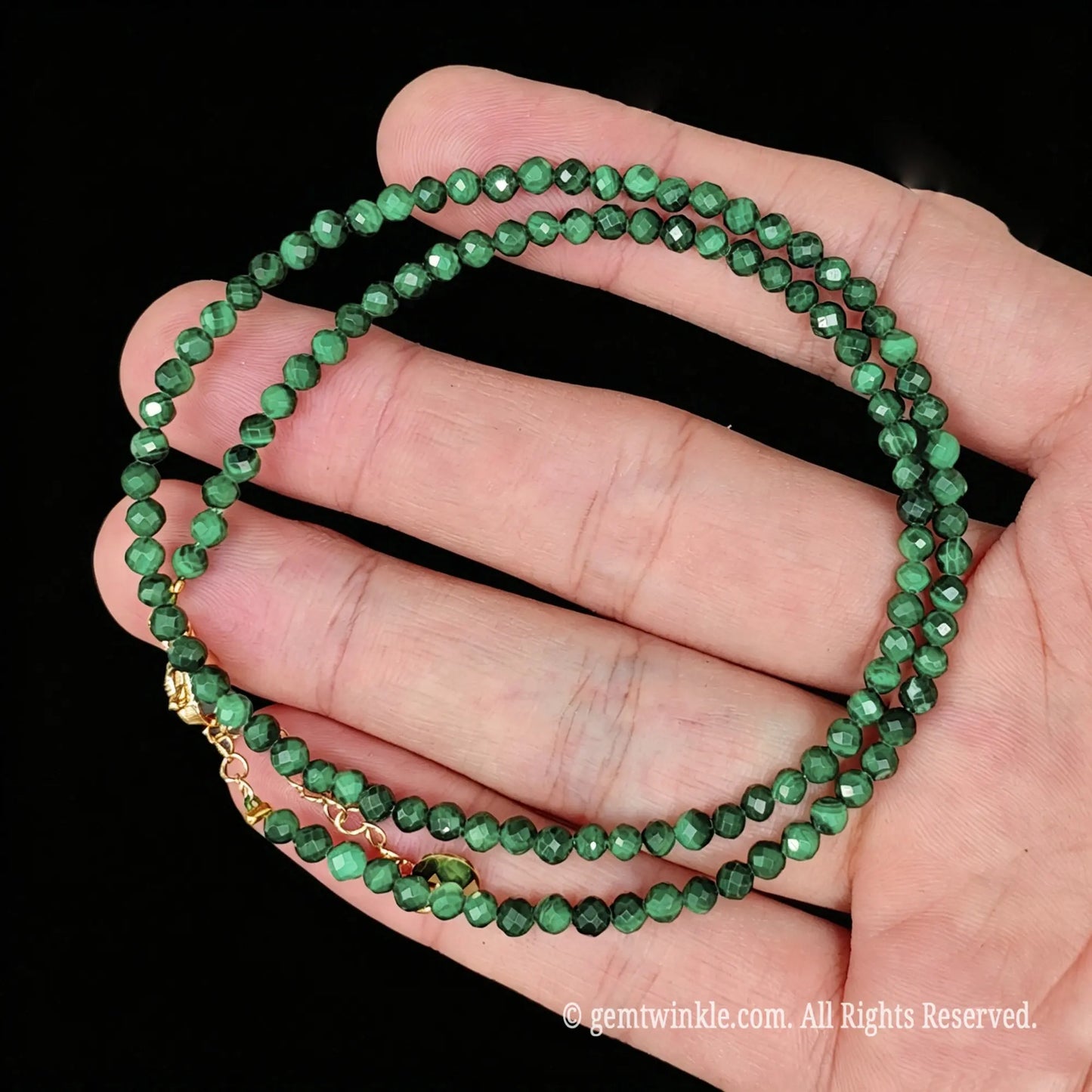 single strand green malachite collar necklace coiled across palm showing banded luster