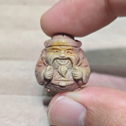 warm yellow and terracotta red natural stone caishen statue held in fingers close up
