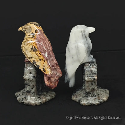 Side view of a hand carved webbed picasso jasper gothic crow figurine sitting on a speckled gray matrix stone tombstone