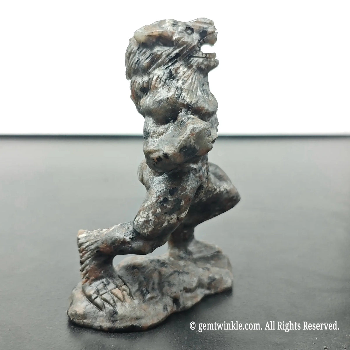 left side profile view of carved werewolf beast sculpture under ambient daylight displaying dark stone texture