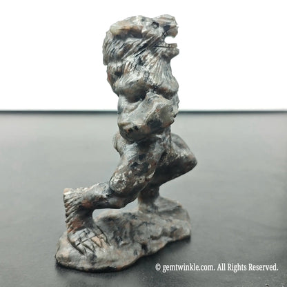 left side profile view of carved werewolf beast sculpture under ambient daylight displaying dark stone texture