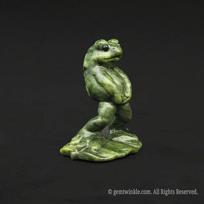Angled side view of a whimsical serpentine stone manneken pis toad carving showcasing its funny posture on a black background