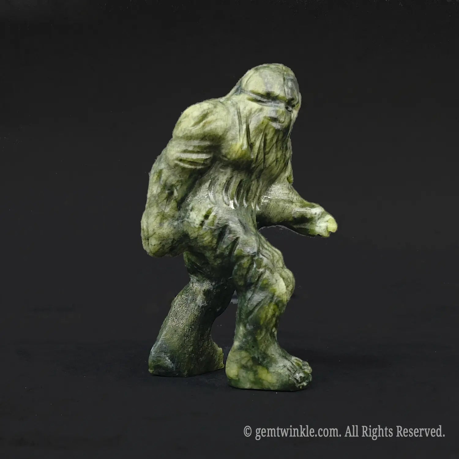 Side angle of a whimsical serpentine stone sasquatch carving displaying mossy olive green yellow fur textures and striding pose