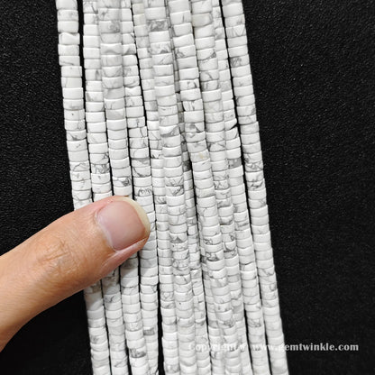 Close up view of 6x3mm white howlite disc rondelle beads held on fingers for quality inspection