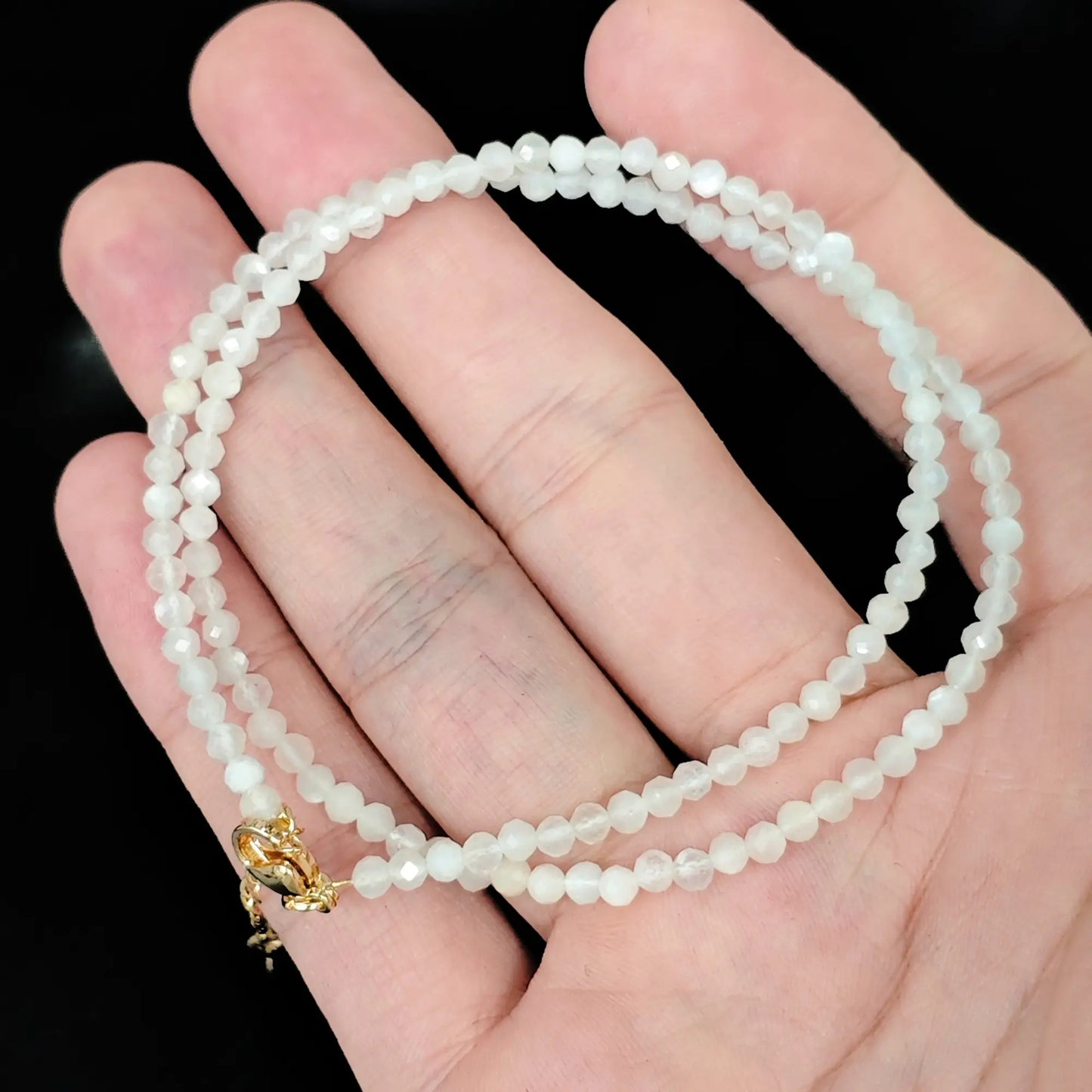 milky white moonstone micro faceted bead strand resting on open hand
