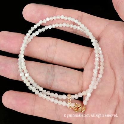 faceted white moonstone micro bead necklace looped with gold extender chain in hand