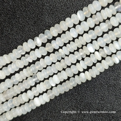 Perspective view of white moonstone smooth heishi spacer beads showing uniform 4mm disc thickness