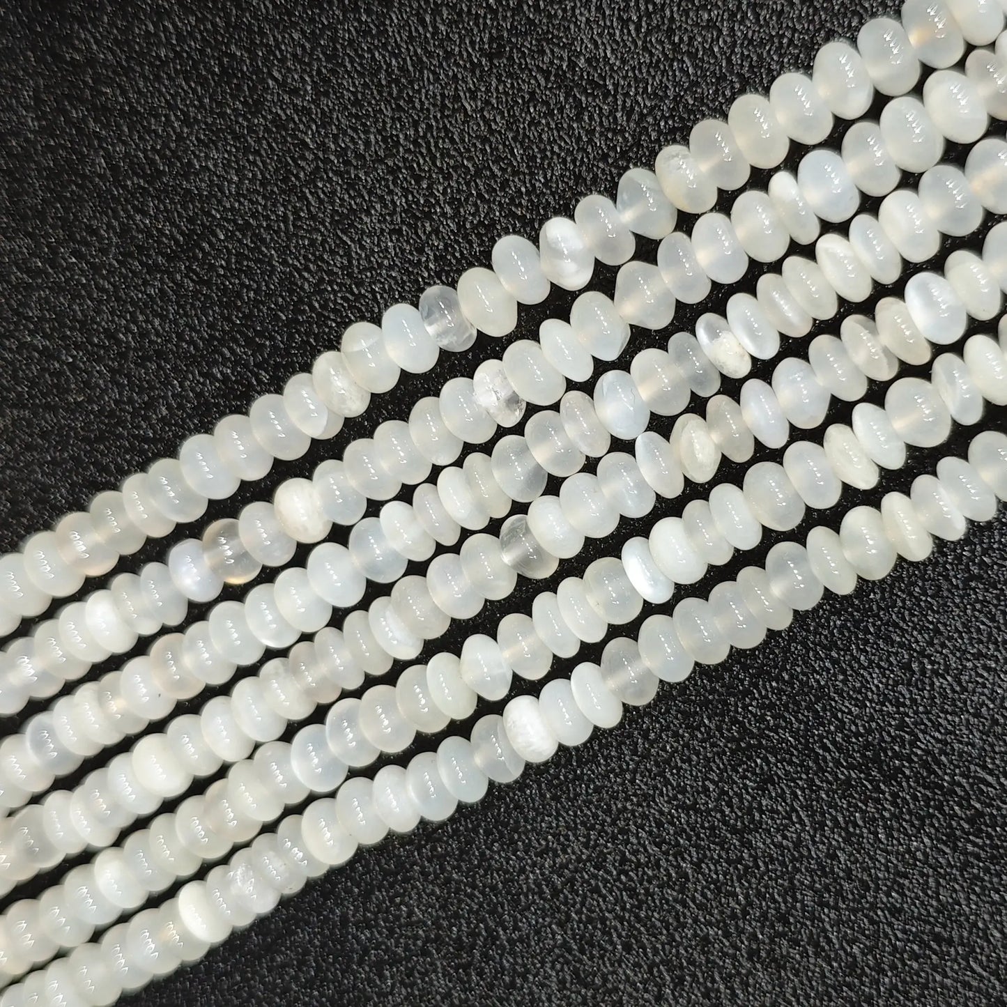 Macro closeup of natural white moonstone smooth rondelle beads 6x4mm showing translucent milky sheen