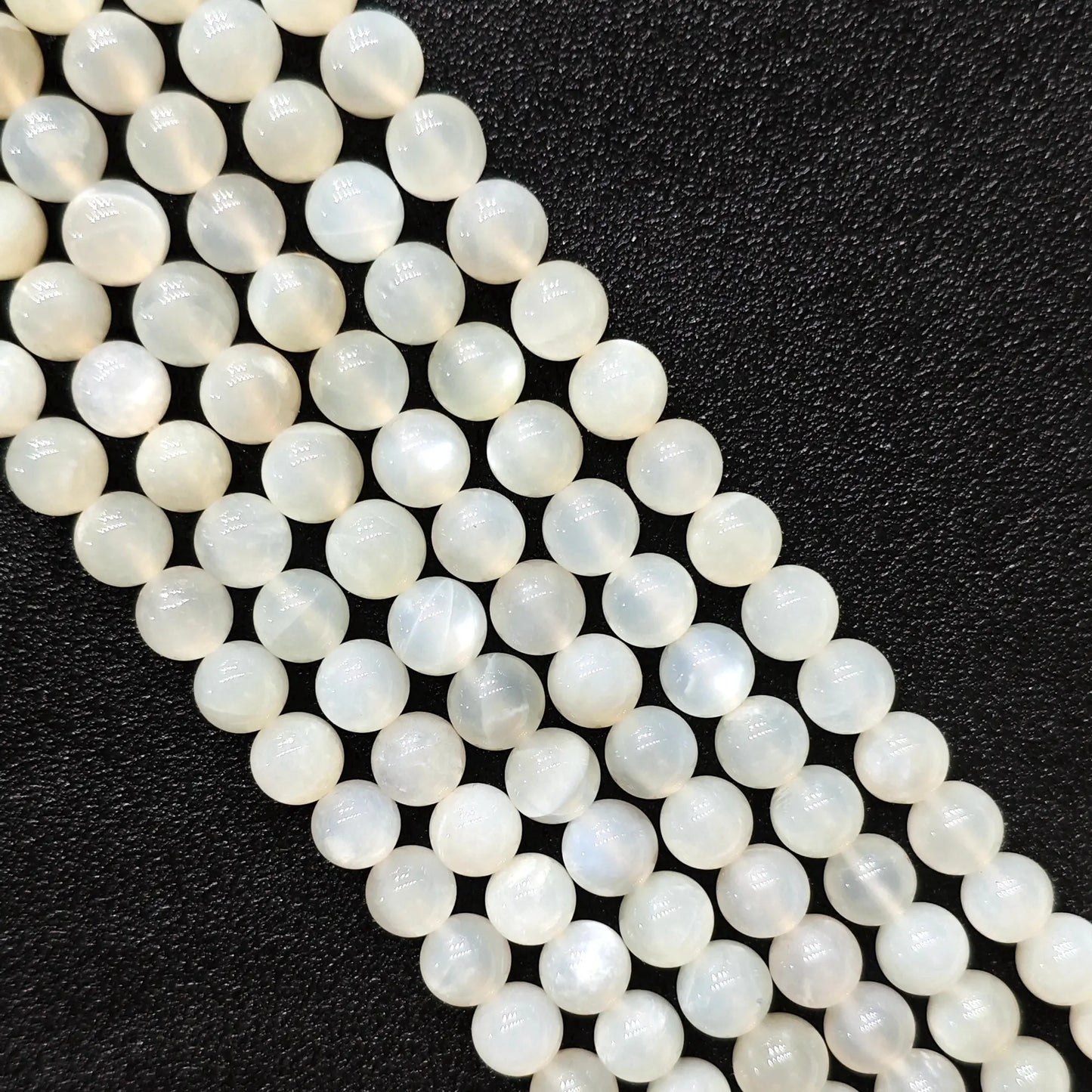 Macro closeup of natural white moonstone smooth round beads showing translucent creamy sheen
