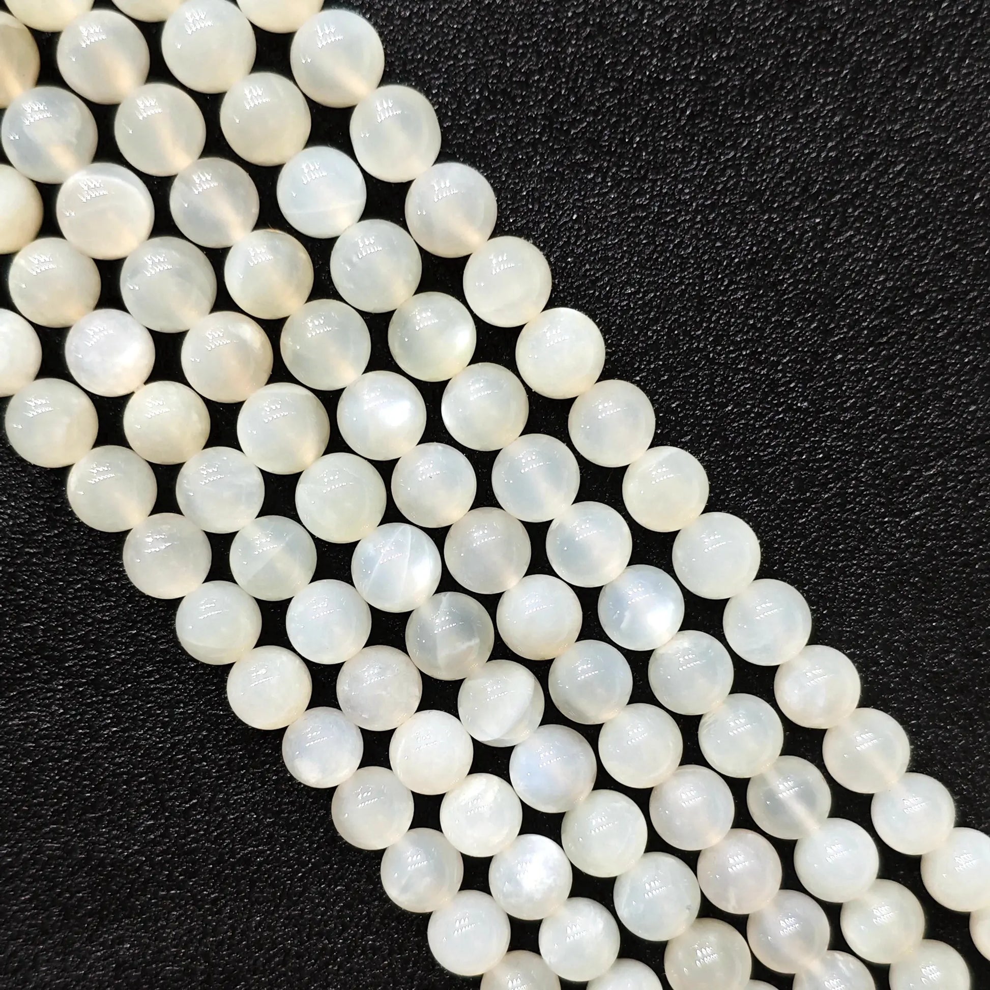 Macro closeup of natural white moonstone smooth round beads showing translucent creamy sheen