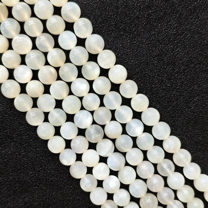 Macro closeup of natural white moonstone smooth round beads showing translucent creamy sheen