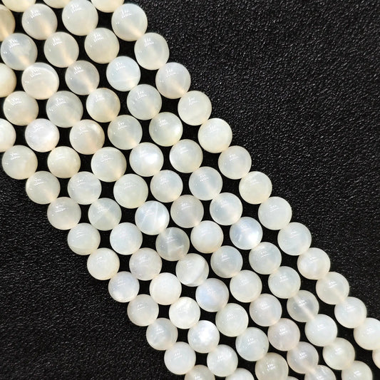 Macro closeup of natural white moonstone smooth round beads showing translucent creamy sheen