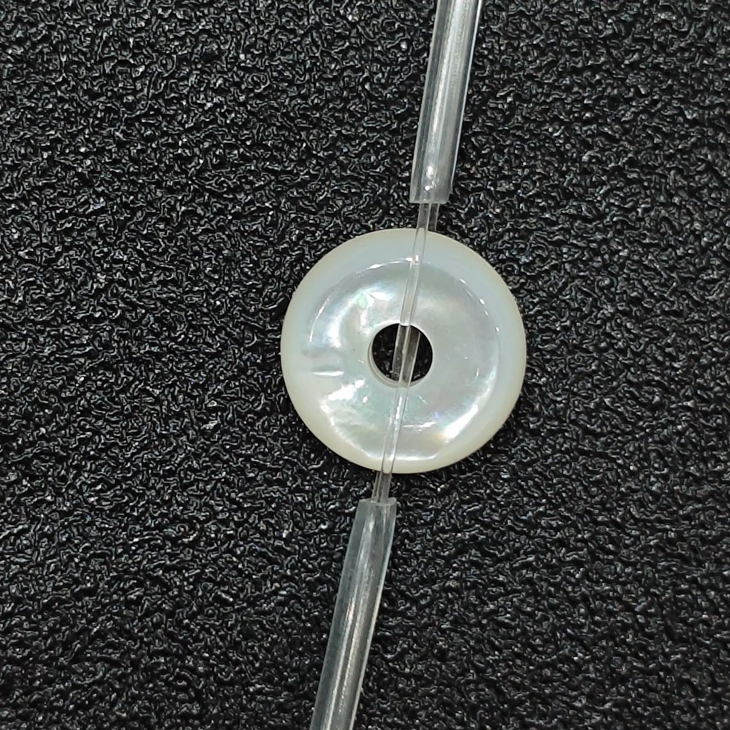 Macro closeup of single natural white mother of pearl flat ring bead 12mm with iridescent sheen