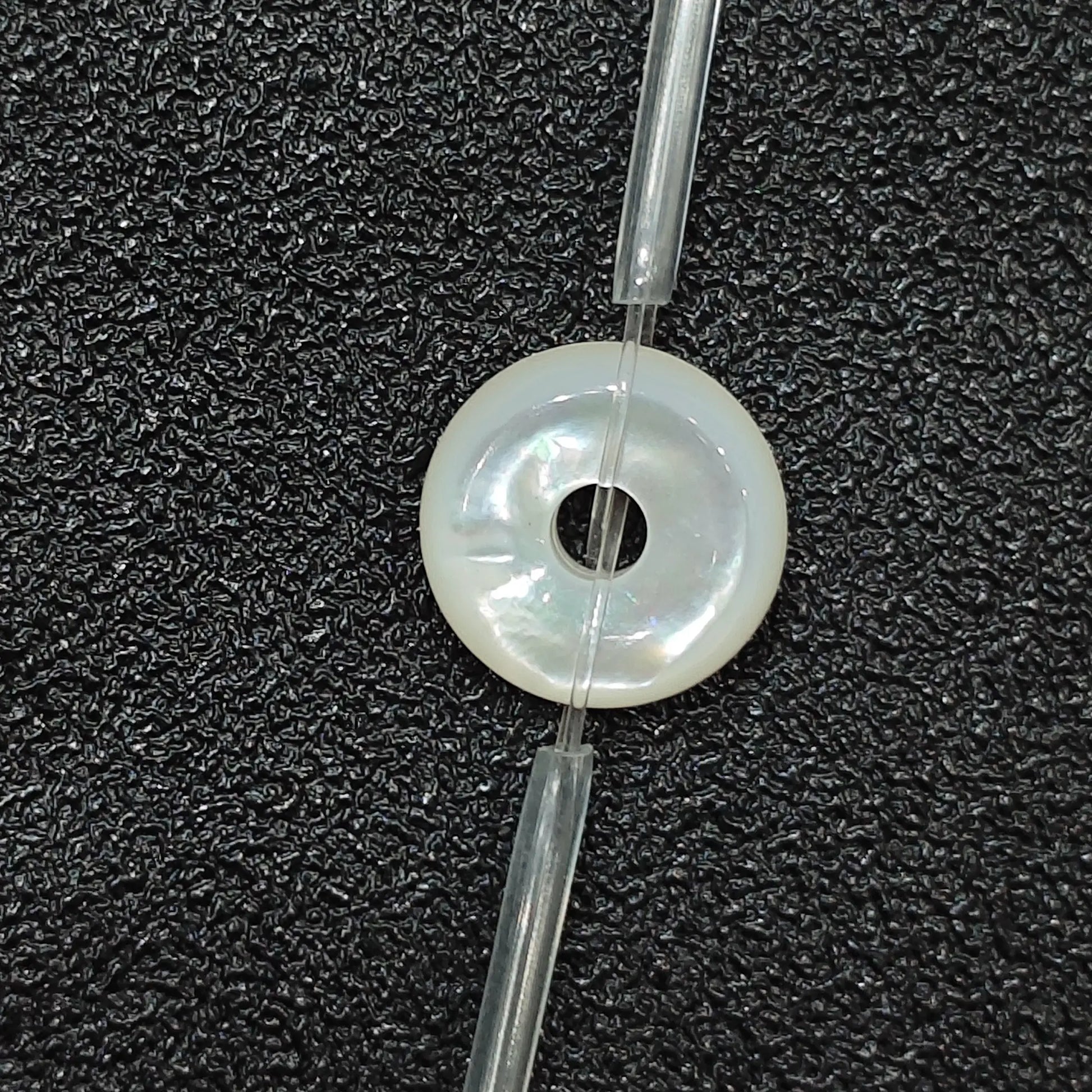Macro closeup of single natural white mother of pearl flat ring bead 12mm with iridescent sheen