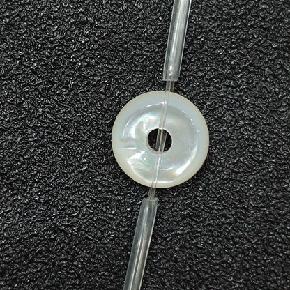 Macro closeup of single natural white mother of pearl flat ring bead 12mm with iridescent sheen