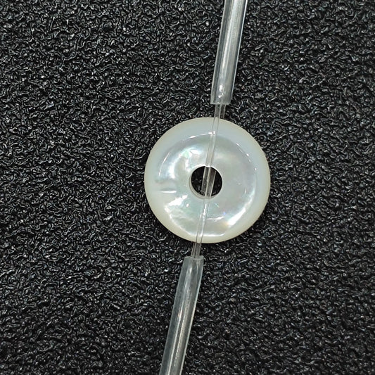 Macro closeup of single natural white mother of pearl flat ring bead 12mm with iridescent sheen