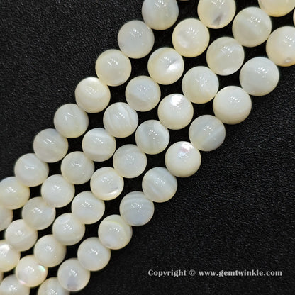 Multiple strands of white mother of pearl round gemstone beads lined up for jewelry supplies