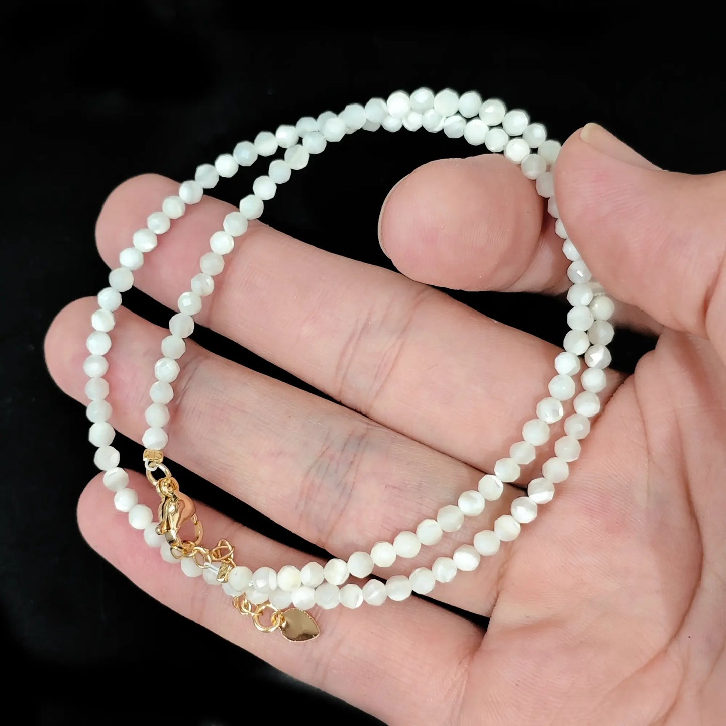 dainty white mother of pearl faceted bead choker rdainty white mother of pearl faceted bead choker resting on open palm with gold clasp