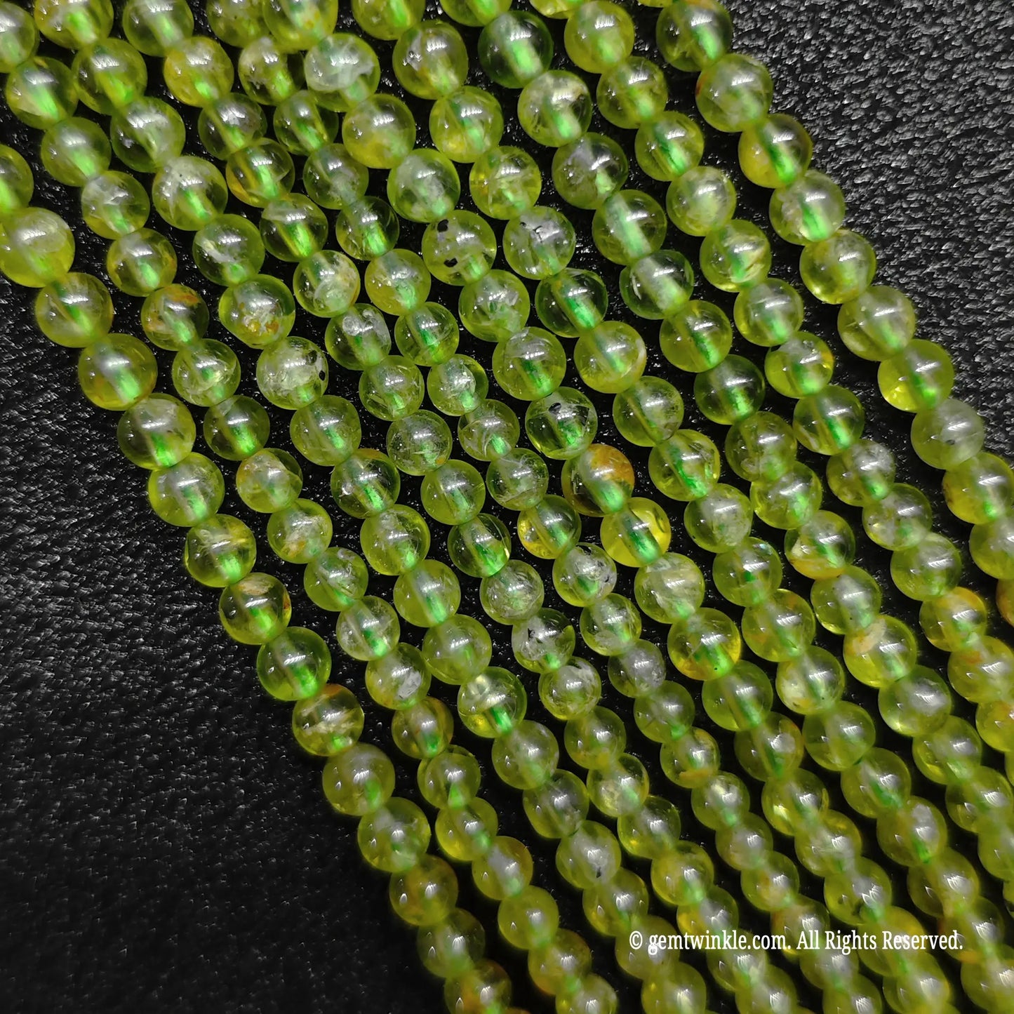 A hand gathering a large bundle of micro B-Grade natural peridot strands to demonstrate volume stock availability and sizing