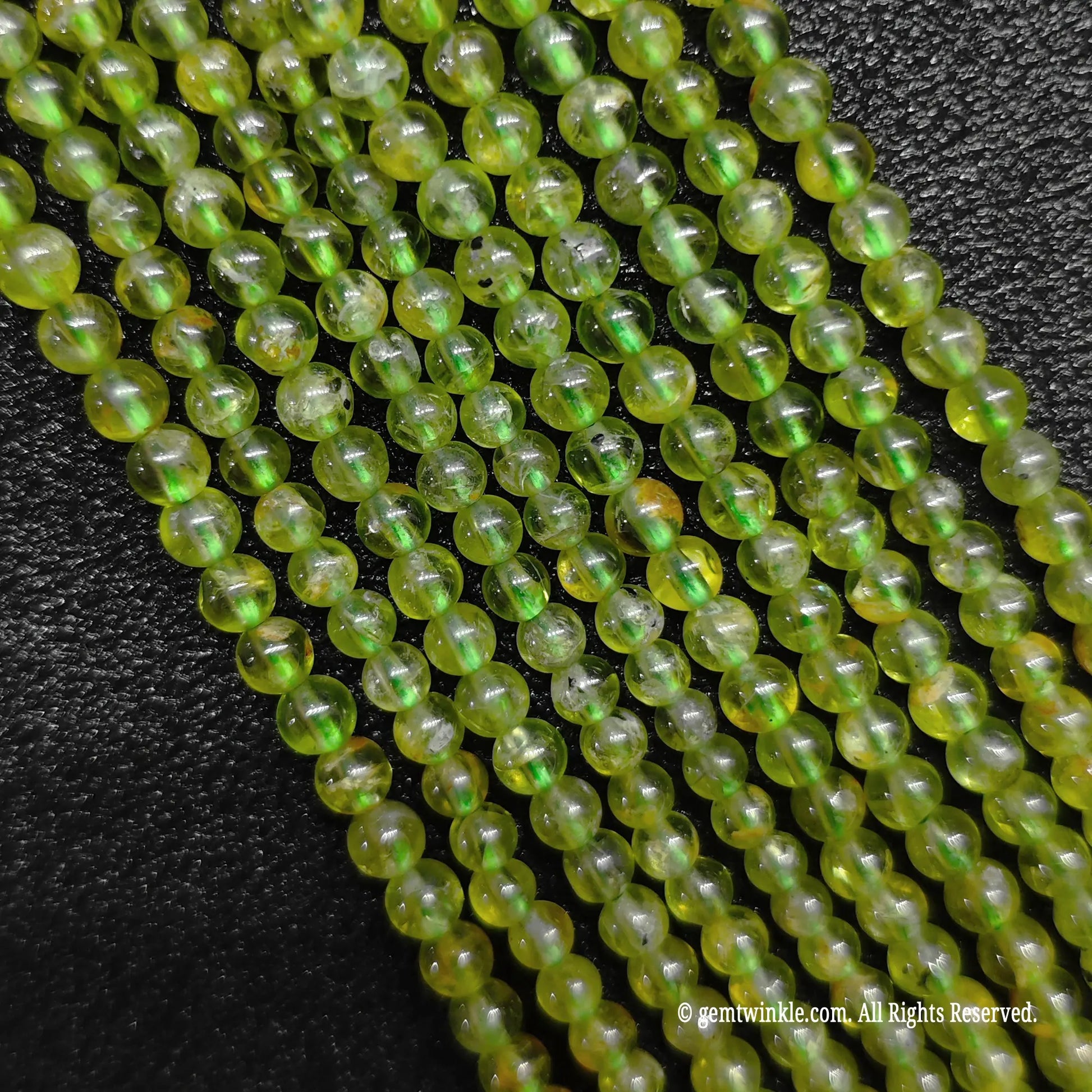 A hand gathering a large bundle of micro B-Grade natural peridot strands to demonstrate volume stock availability and sizing