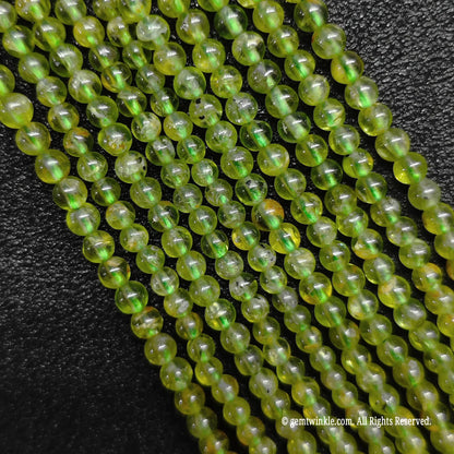 A hand gathering a large bundle of micro B-Grade natural peridot strands to demonstrate volume stock availability and sizing
