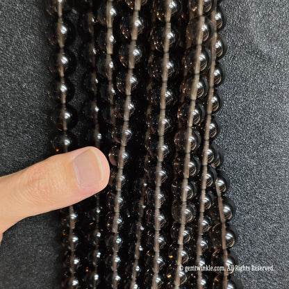 Hand holding multiple strands of natural ice obsidian crystal beads showcasing the full size choice grid
