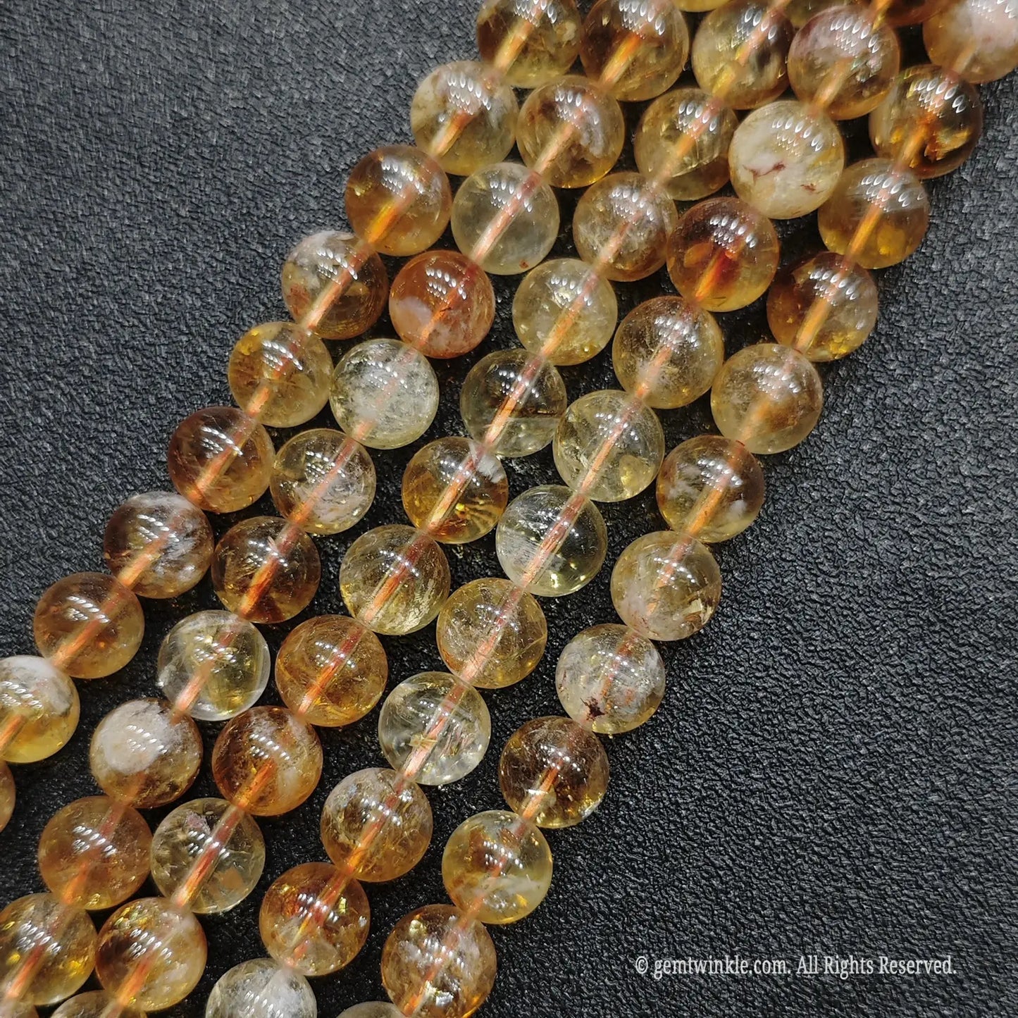 Detailed macro display of wholesale luminous honey citrine round beads emphasizing minimal white cotton patterning