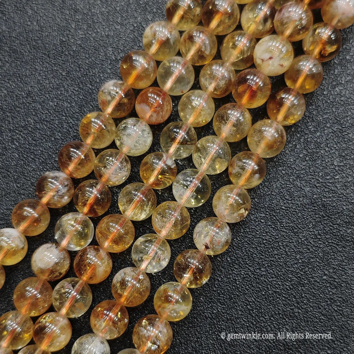 Detailed macro display of wholesale luminous honey citrine round beads emphasizing minimal white cotton patterning
