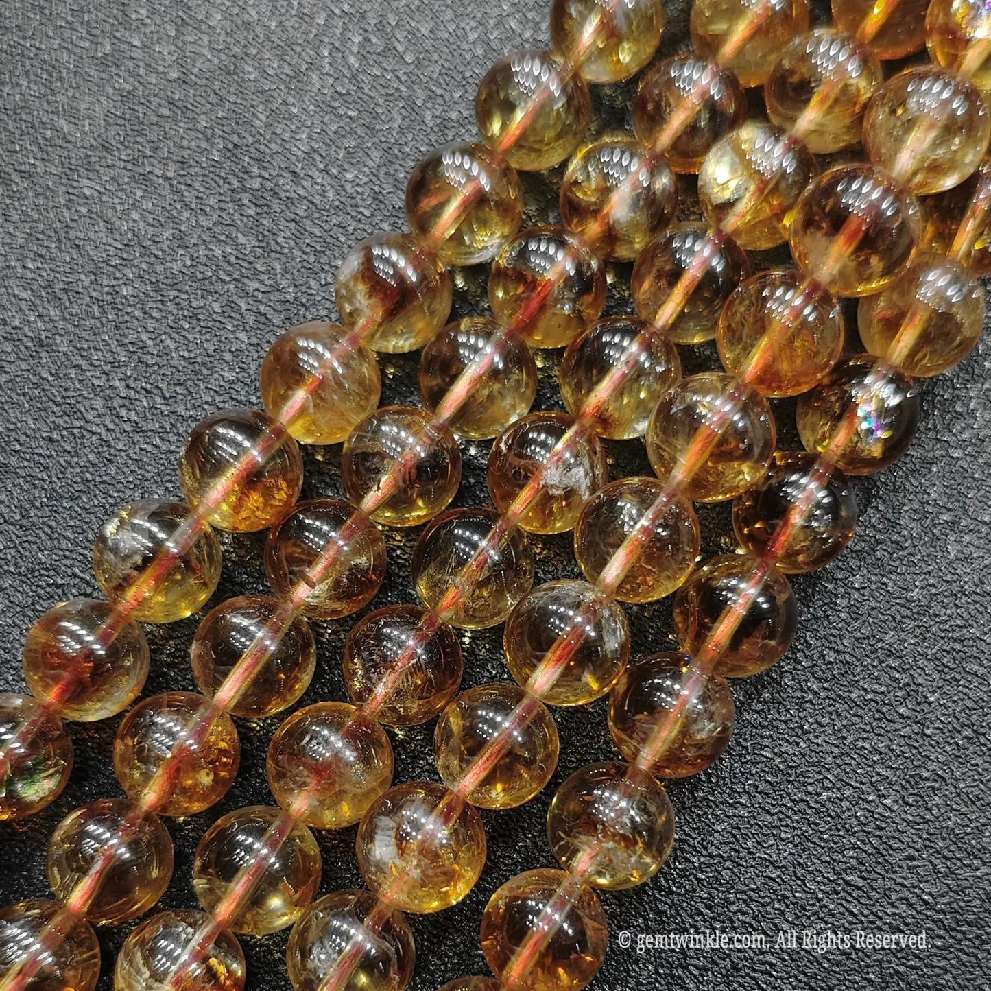 Close up birds eye look of wholesale luminous honey citrine round beads emphasizing beautiful contrast between crystal transparency and white veining