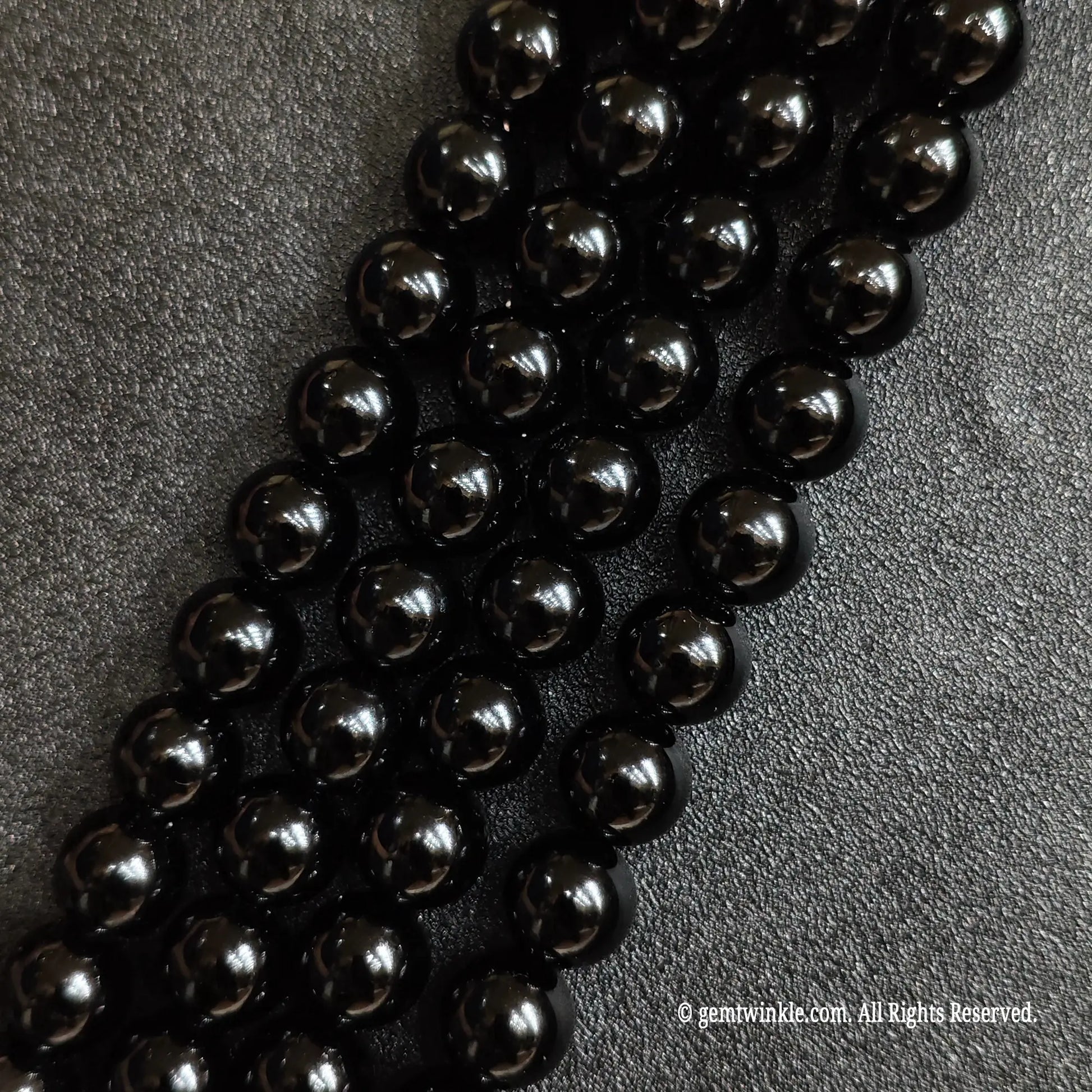 Close up of natural pure black obsidian crystal beads strands with deep jet black reflections